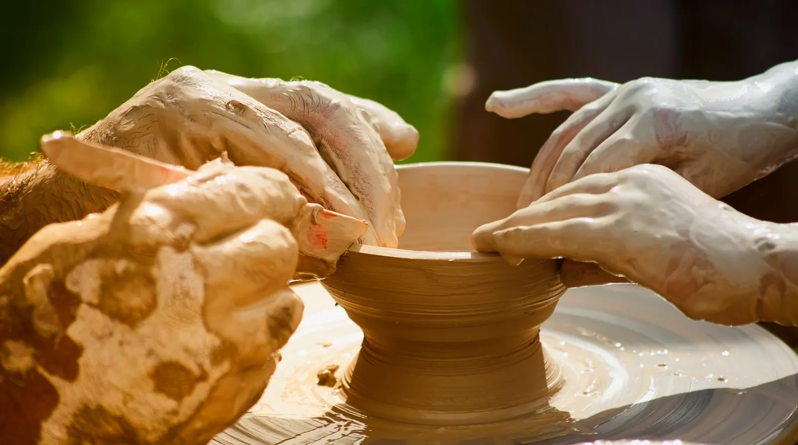 Hands shaping clay on a pottery wheel, creating an artisan pot.